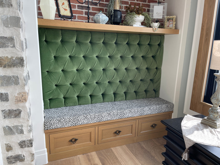 Green velvet wall panel with ornate tufting that adds contrast to bench cushion.